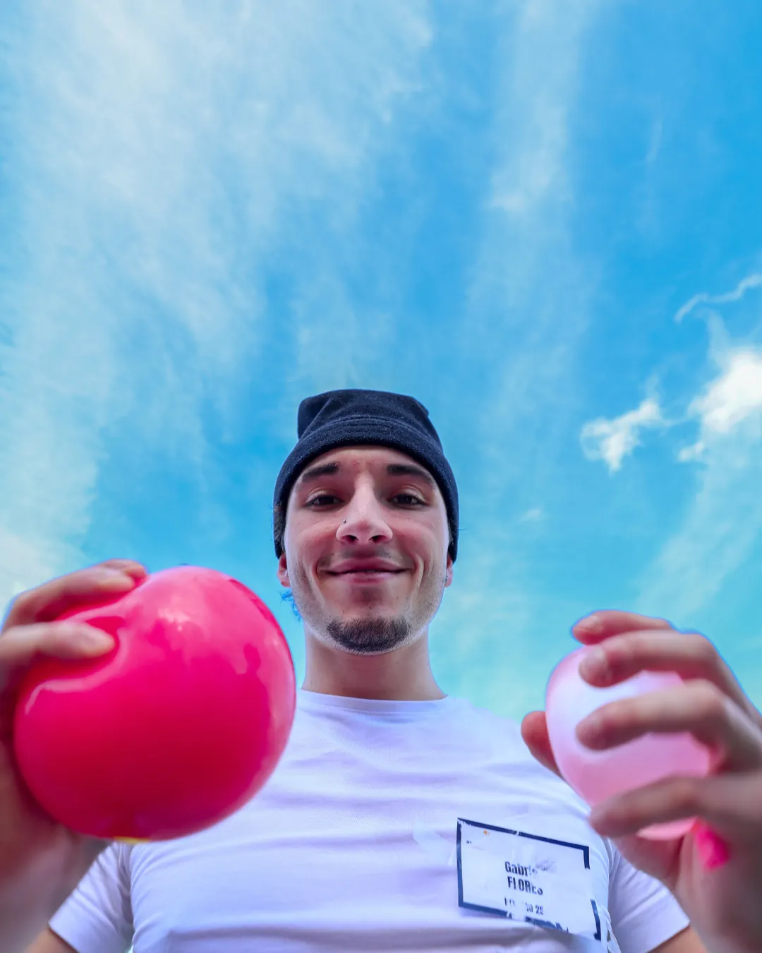 Jeune homme souriant tenant deux balles, photographié en contre-plongée