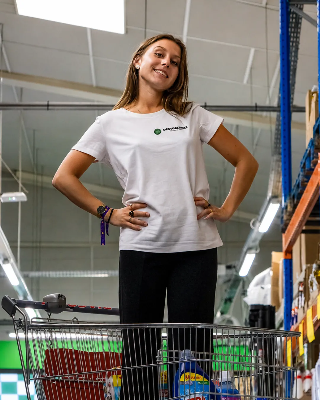 Salariée de Destockman debout dans un caddie en magasin