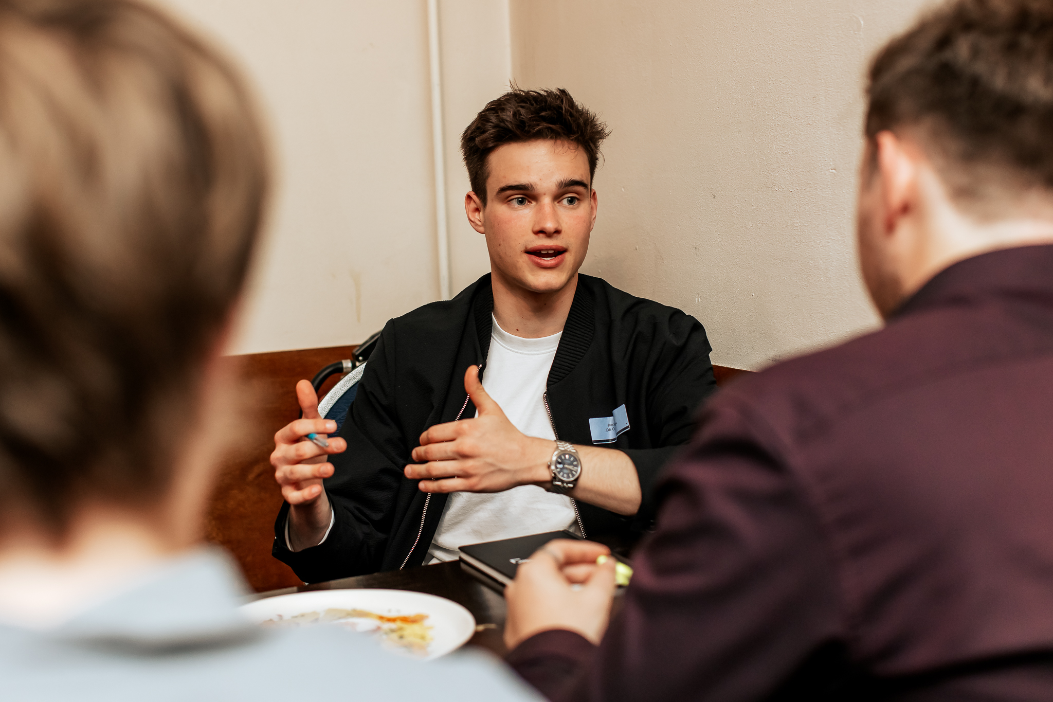 Goochelaar Jonas De Bruyn legt magische kaarttruc uit aan ondernemers tijdens zakelijk event, entertainment en interactie aan tafel in inspirerende setting.