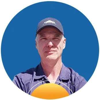 Man wearing a navy blue cap and shirt standing against a solid blue background.