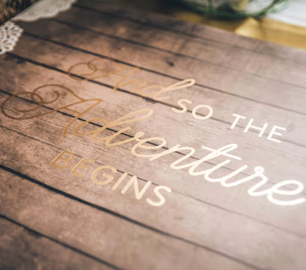 a picture of wood with gold writing saying - and so the adventure begins