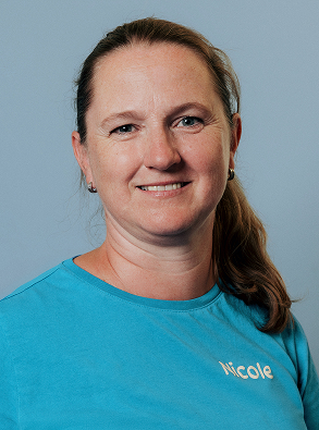 Smiling woman with light brown hair tied back wearing a blue shirt with the name Nicole.