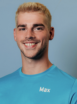 Smiling young man with short blond hair wearing a blue shirt with the name Max on it against a plain blue background.