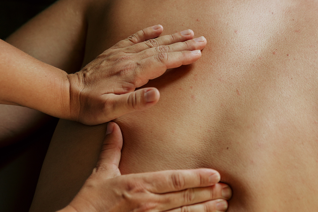 Hands performing a therapeutic massage on a person's back.