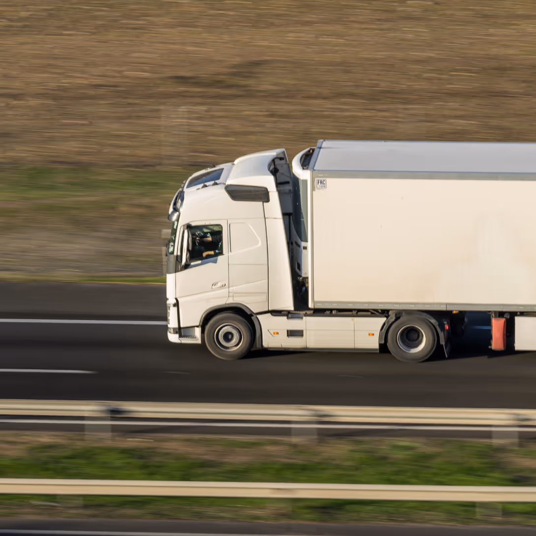 A white semi truck is driving down a road.