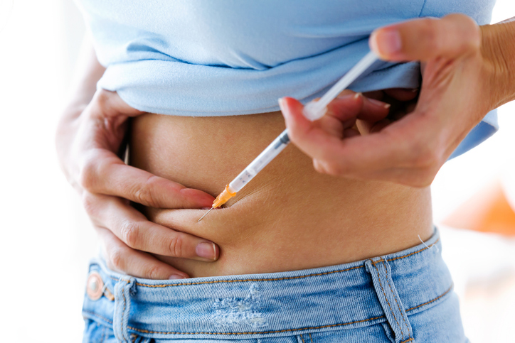  Person administering a weight-loss injection in the abdomen using a syringe.