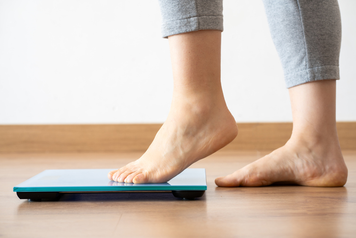 Person standing on a bathroom scale while tracking weight-loss progress during a GLP-1 treatment program.