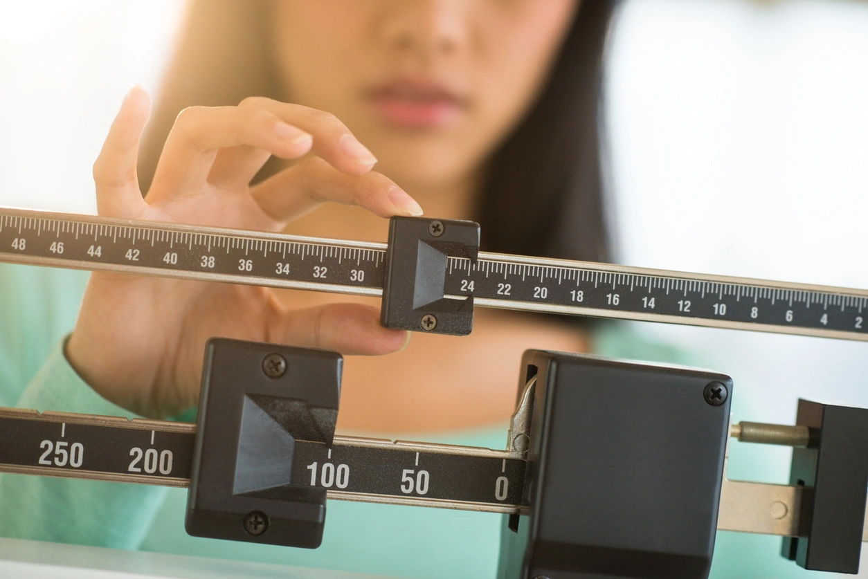 Woman standing on a medical weight scale during a routine health assessment while tracking progress on semaglutide therapy.