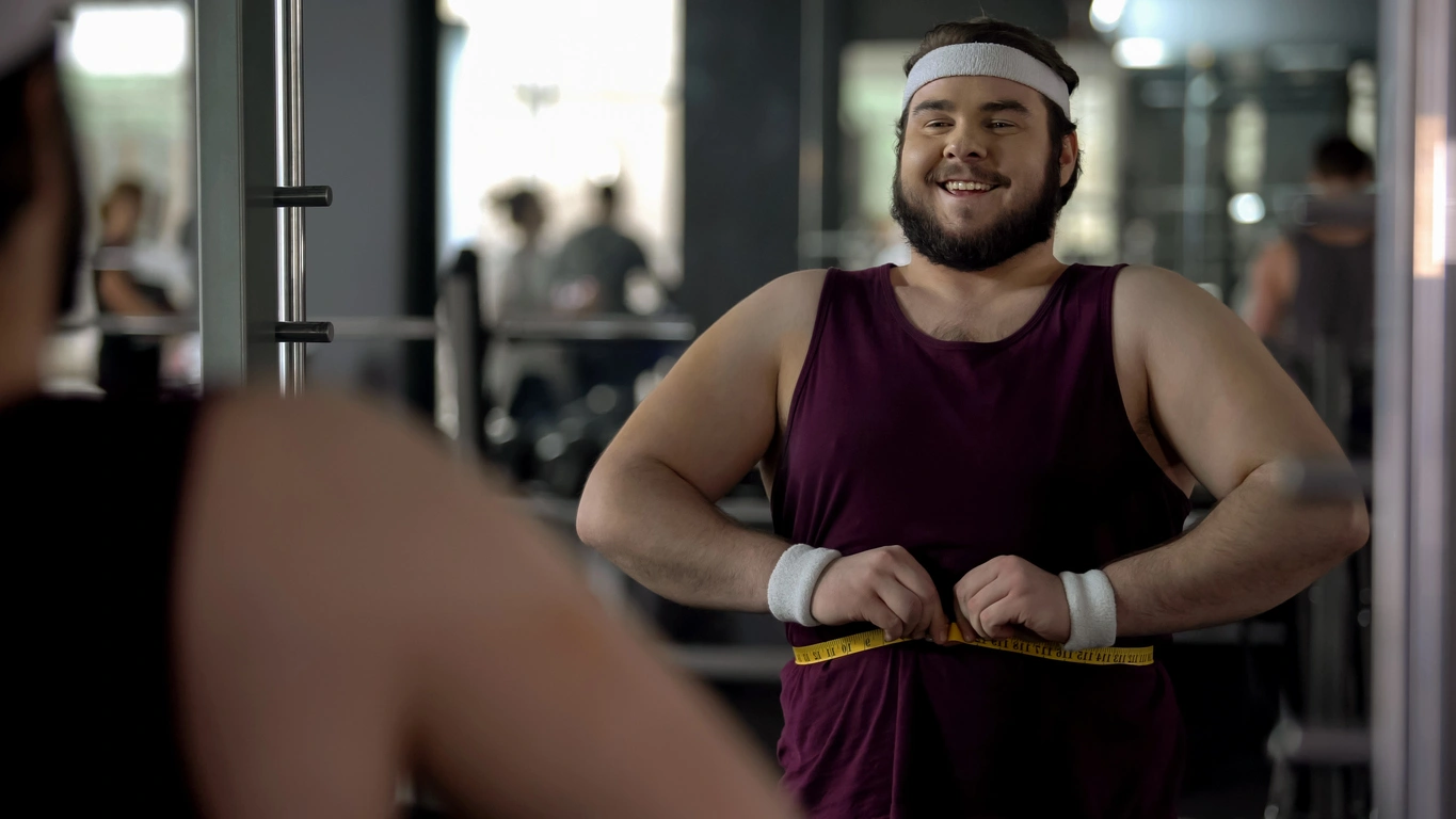 Man measuring his waist at the gym while monitoring body composition changes during a semaglutide weight loss program.
