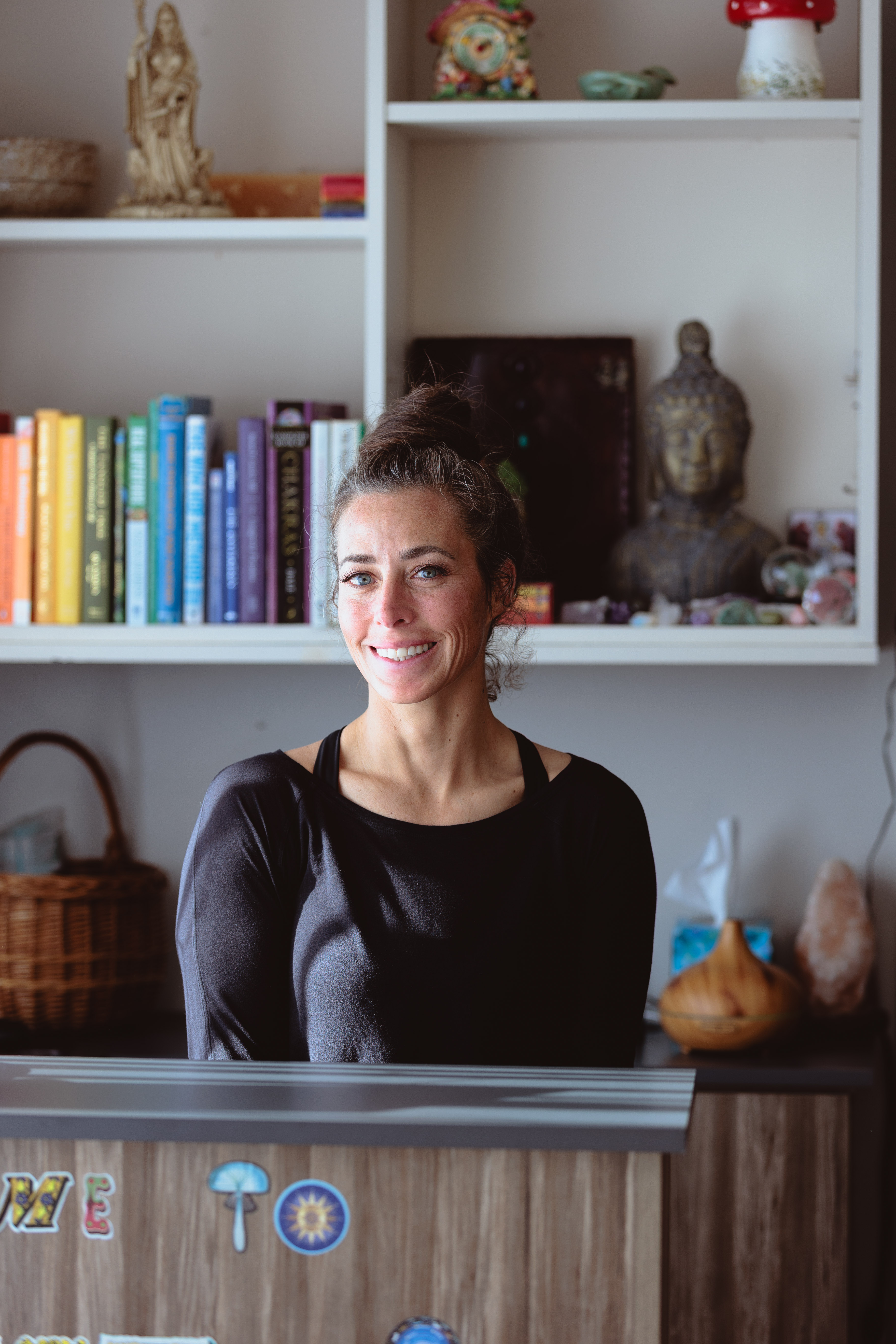 Person performing a forearm balance yoga pose with one leg bent and the other extended upward on a wooden floor.