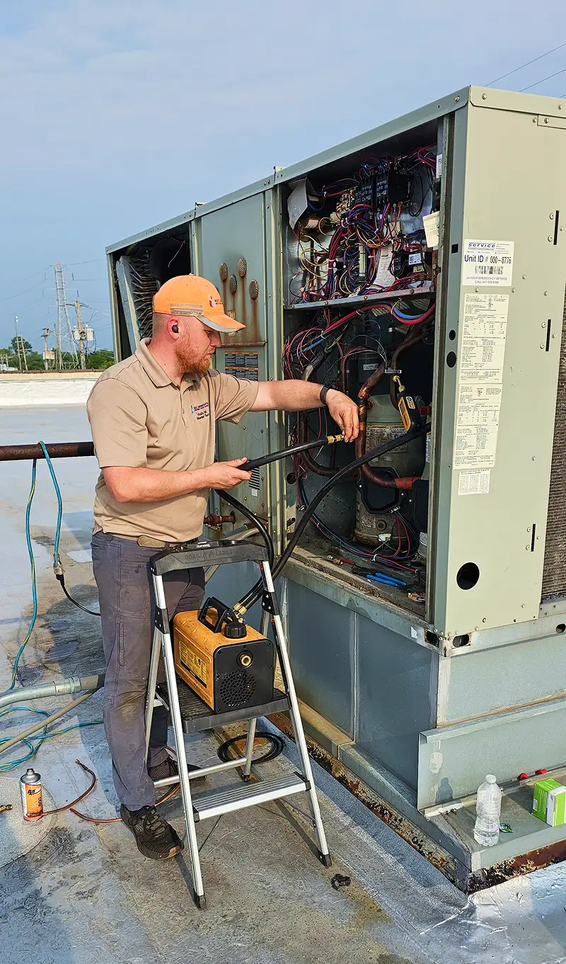 HVAC technician repairing rooftop commercial air conditioning system.