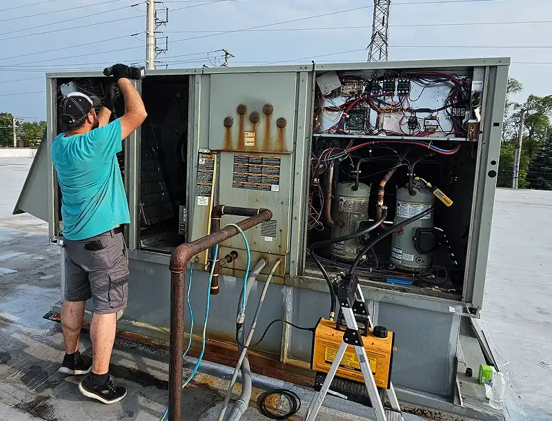 Technician performing maintenance on commercial HVAC unit