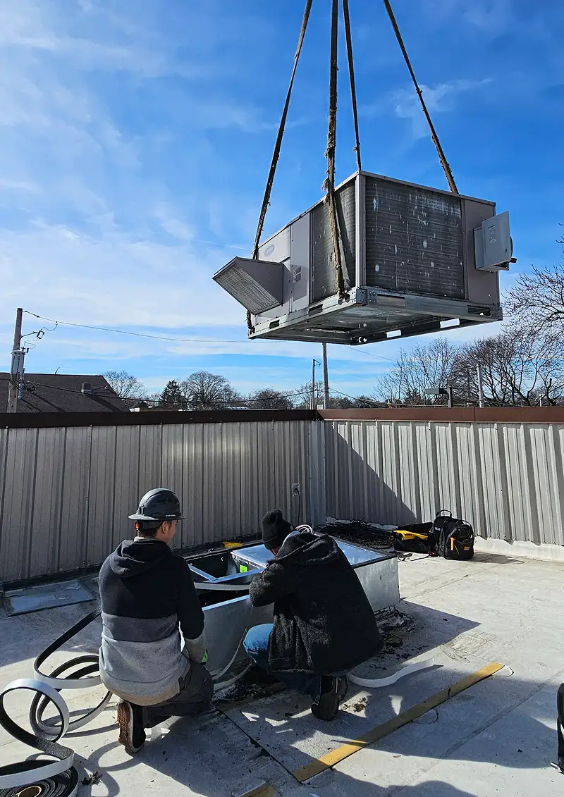 Technicians installing a rooftop HVAC unit