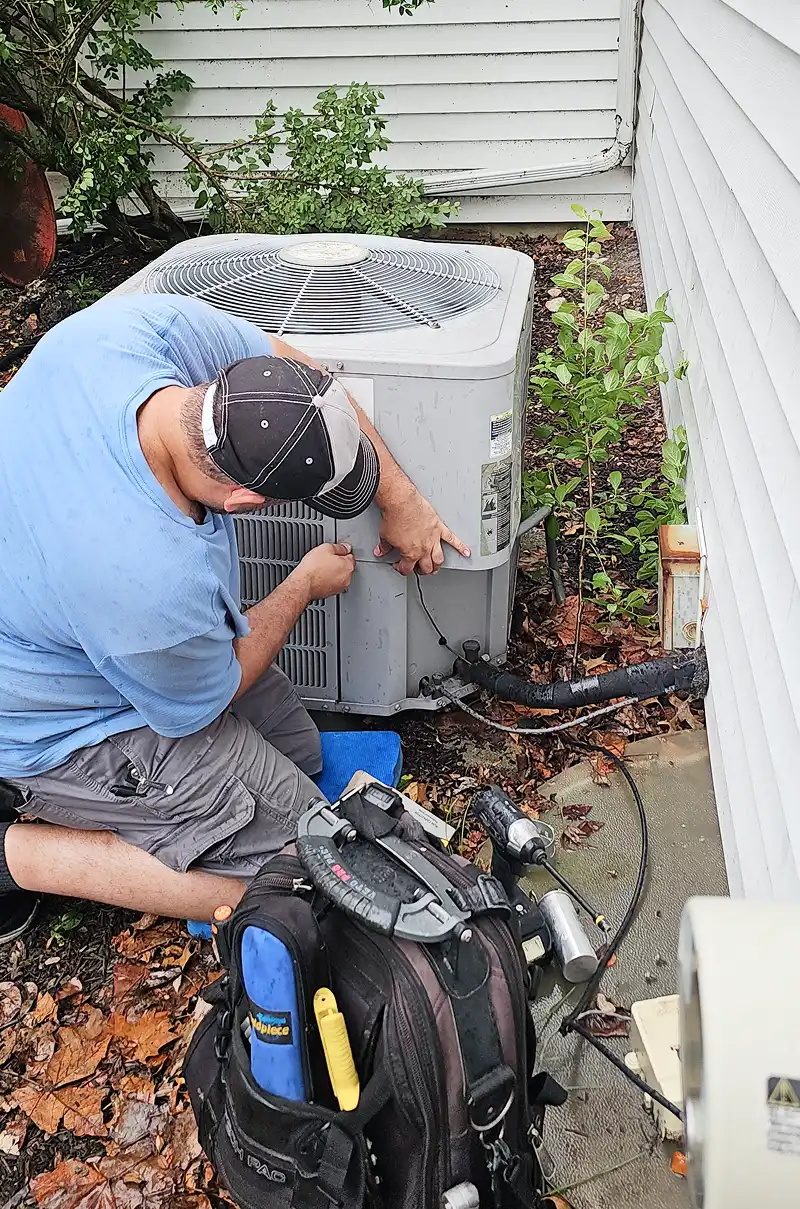 HVAC technician repairing an outdoor air conditioning unit.