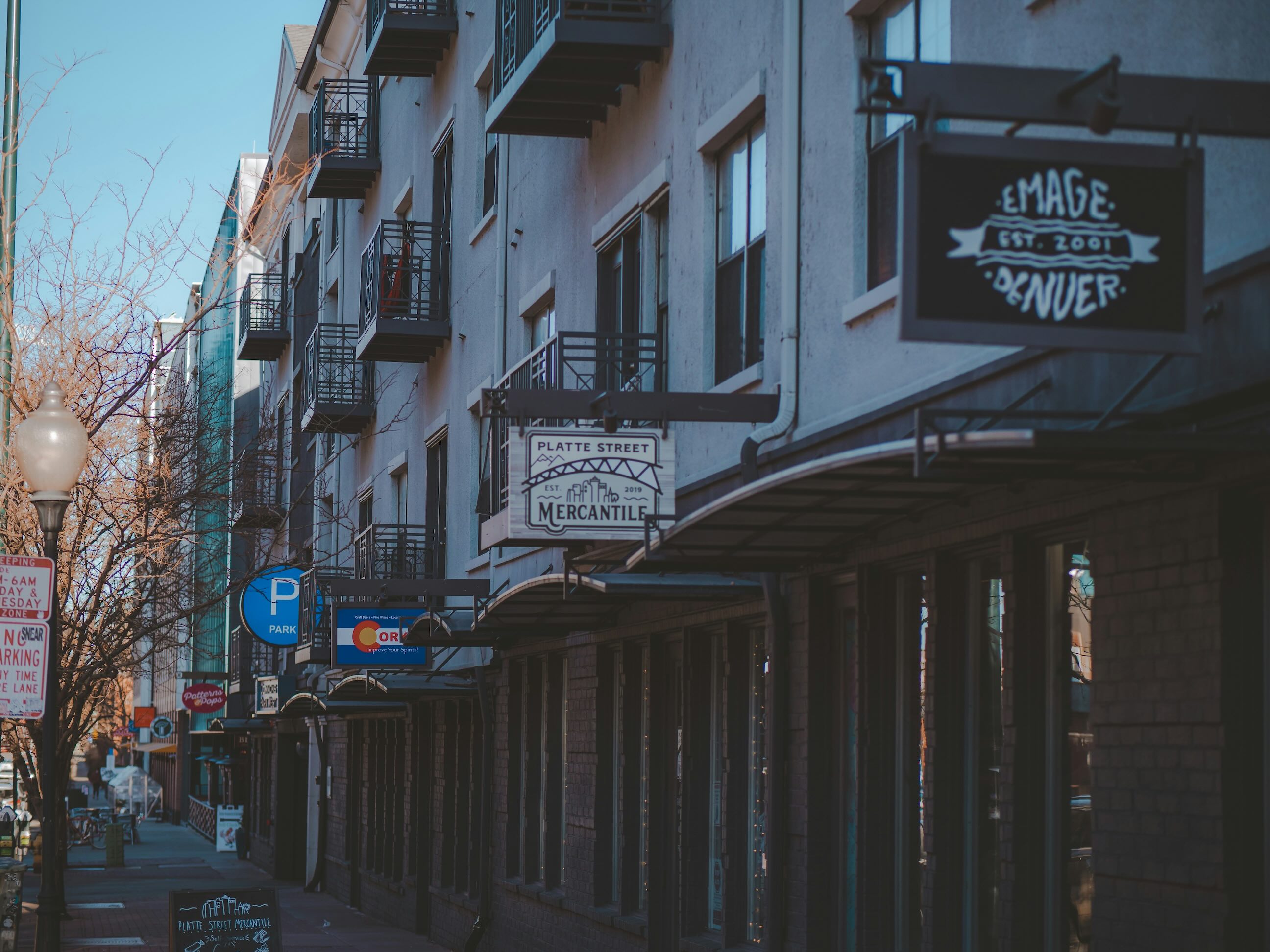 Denver’s Platte Street storefronts with hanging signs and small balconies on a clear winter day.