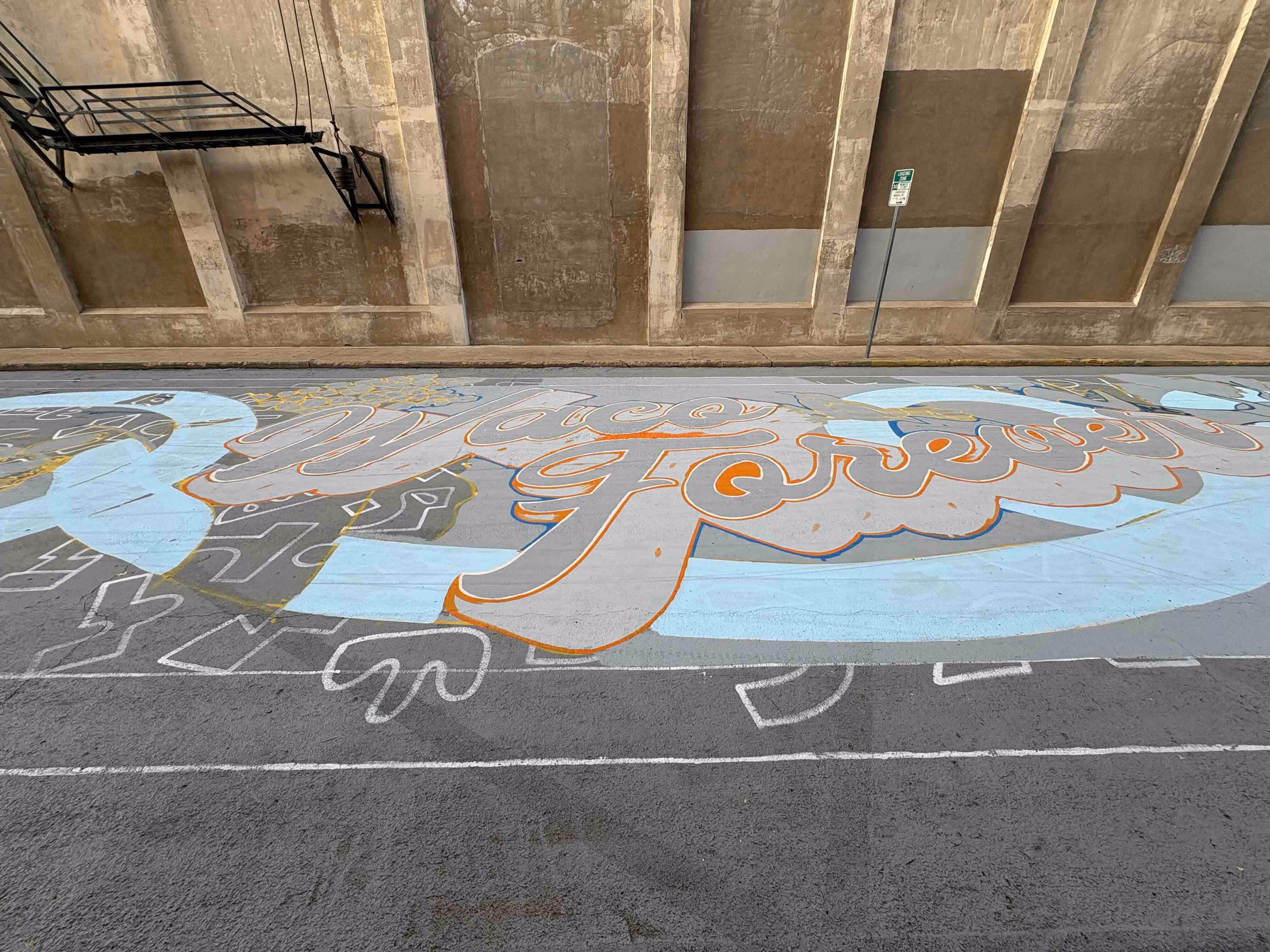 A large street mural on asphalt reading 'Waco Forever' in stylized, colorful lettering against a beige concrete wall.