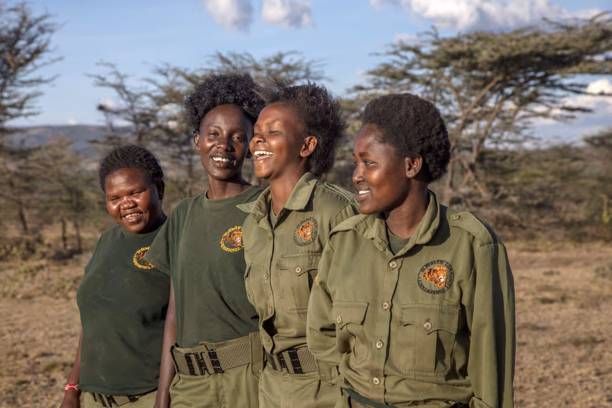 Four female Maasai rangers smiling during a patrol in the Olderkesi Conservancy, Kenya.