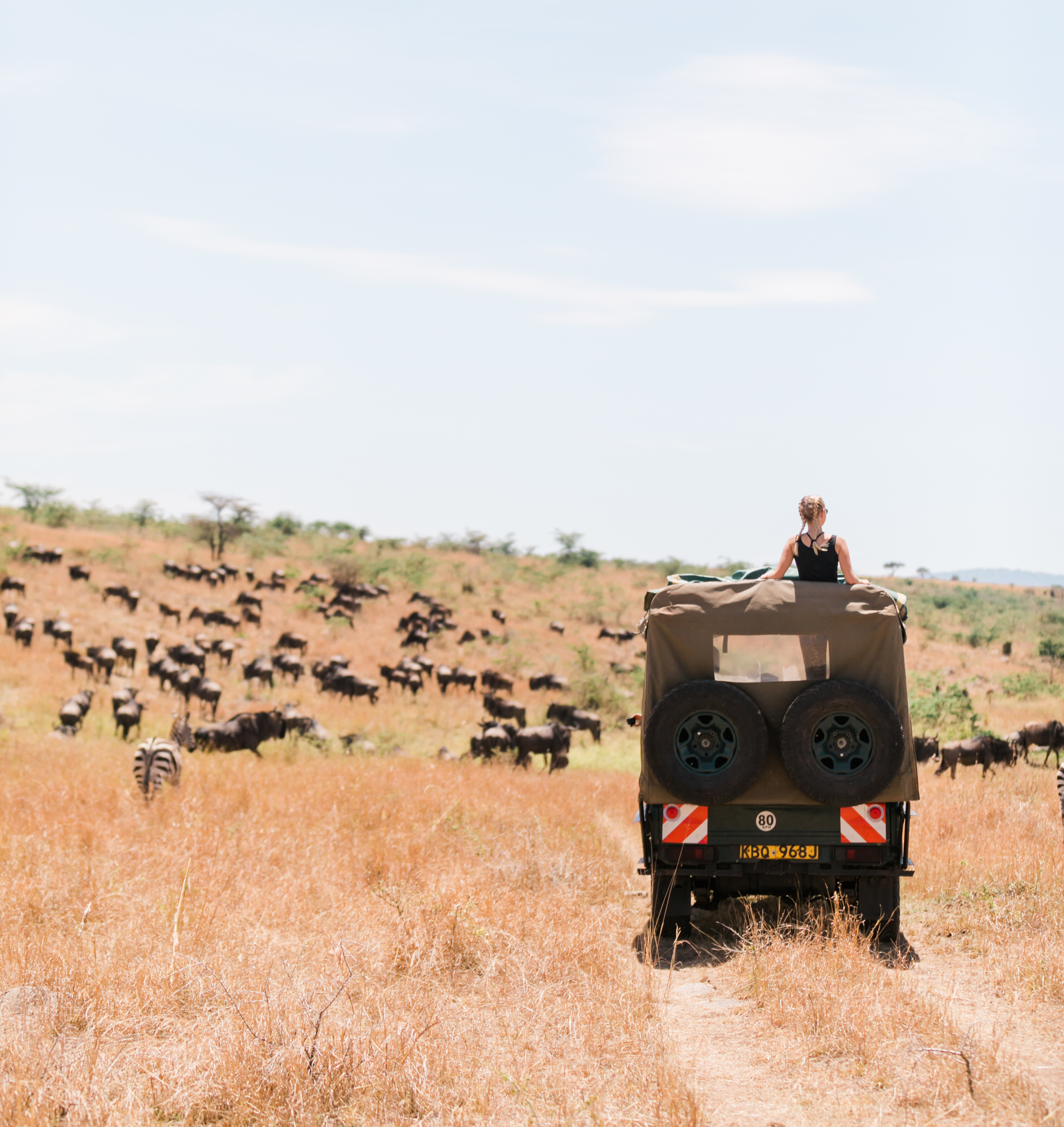 Guest and Maasai guide riding e-bikes across the open plains of the Maasai Mara under blue skies.
