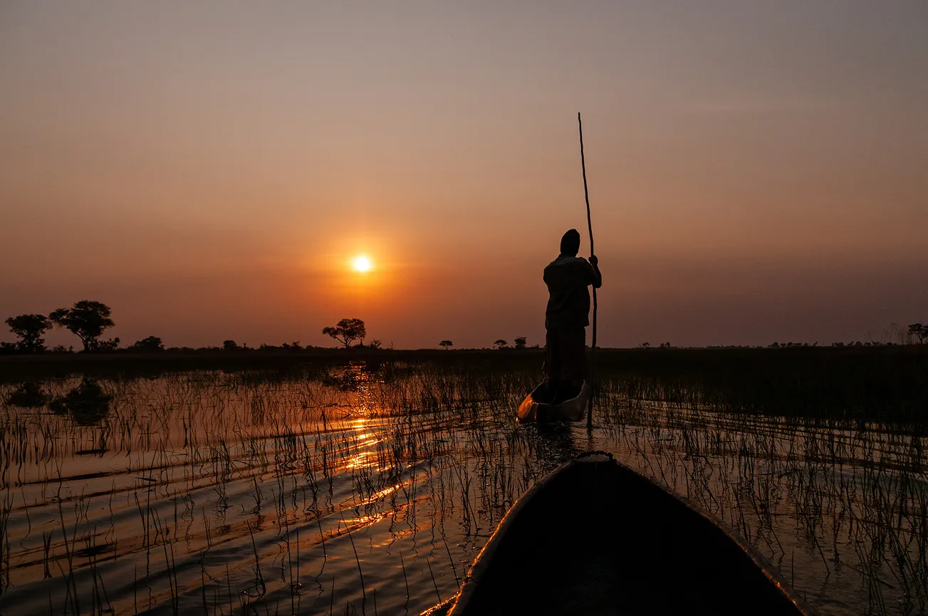 Mokoro canoe at sunset in the Okavango Delta, representing remote Southern Africa safari journeys.