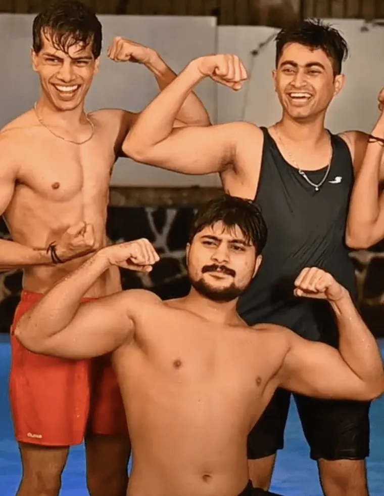 Three fit friends flexing muscles and smiling in gym setting