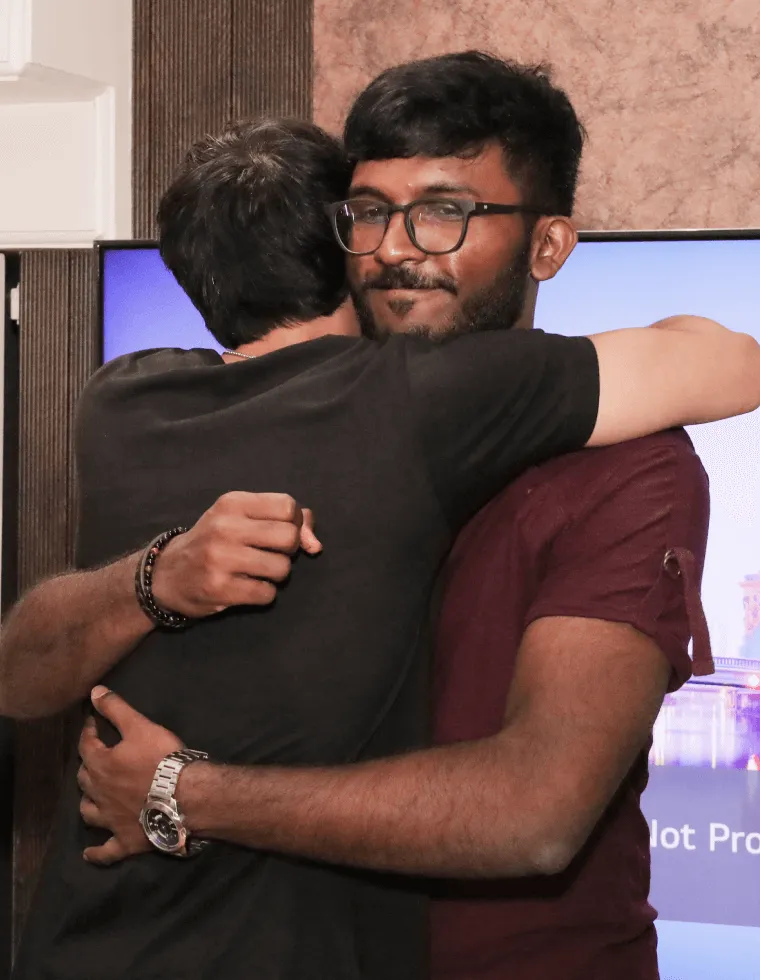 Two men hugging in front of computer screens, showing emotional connection