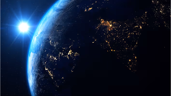 Earth at night from space, showing city lights against dark planetary surface