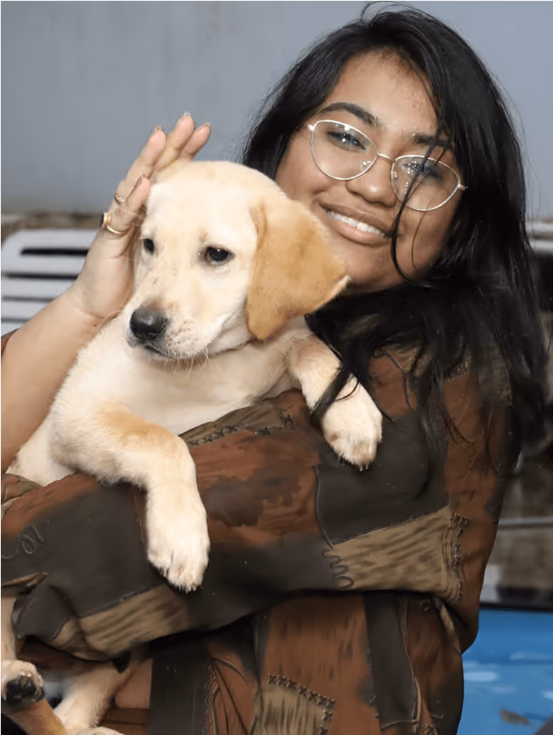 Smiling woman in glasses holding adorable yellow Labrador puppy
