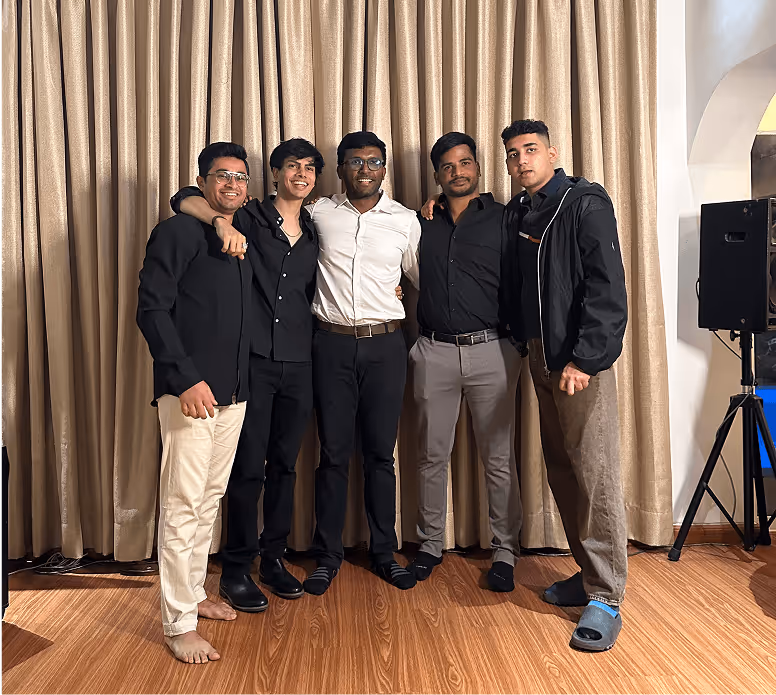 Five men in black and white outfits posing together by curtained backdrop