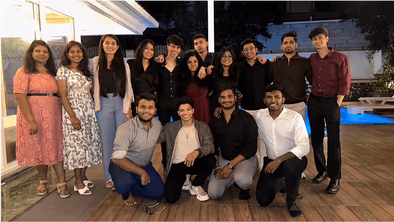Group photo of young professionals posing together near a swimming pool at night