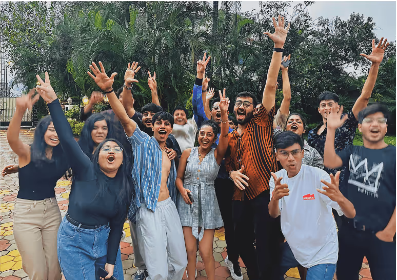 Excited group of young people cheering and raising hands together outdoors