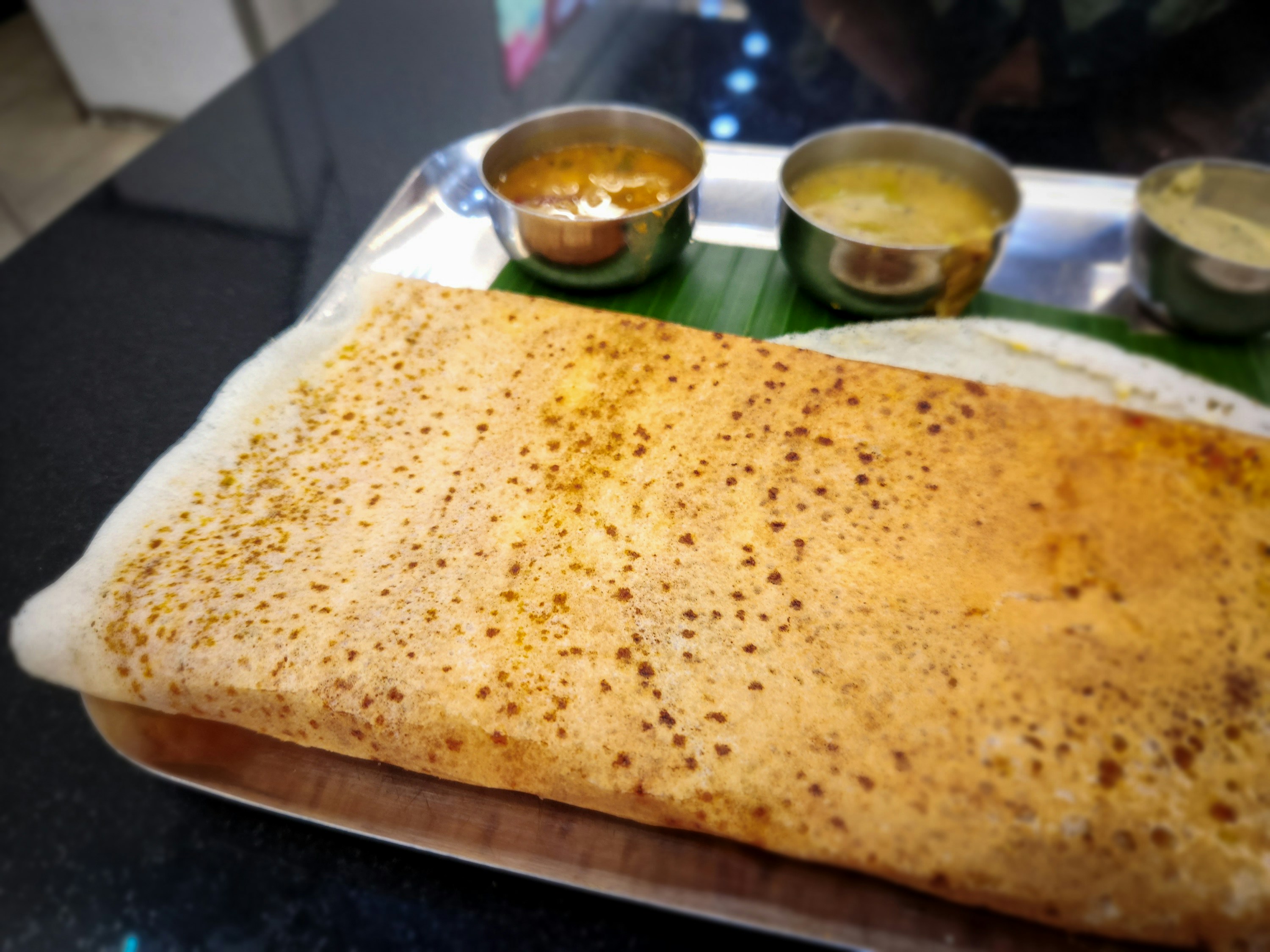 Crisp South Indian dosa served on a banana leaf with sambar and chutneys