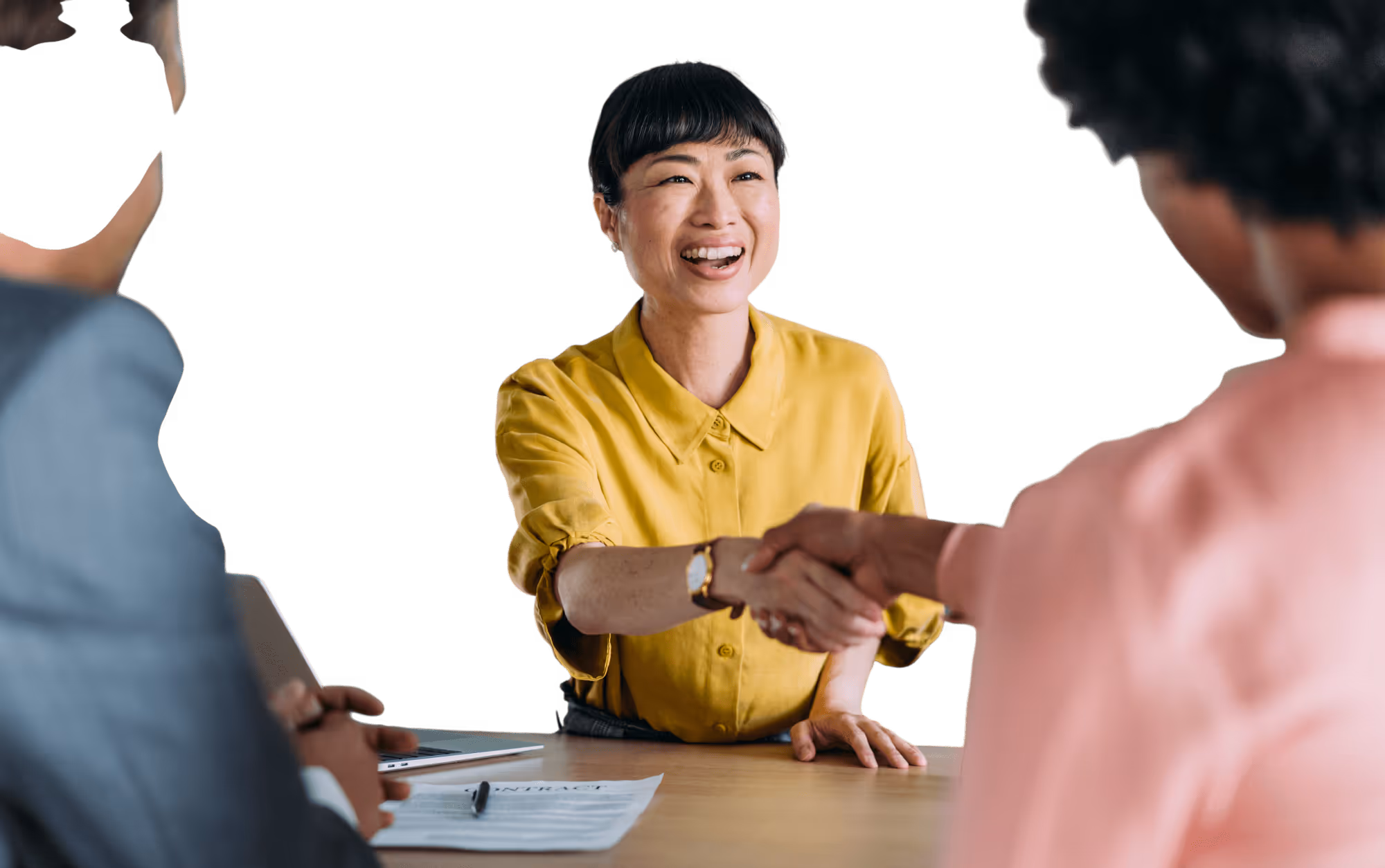Smiling woman in a yellow shirt shaking hands with another person during a meeting.