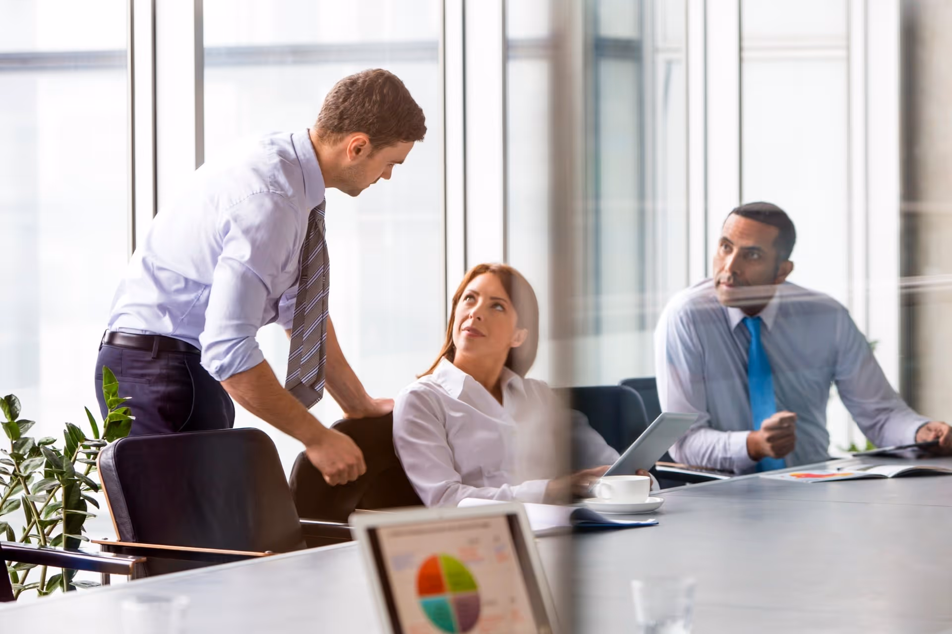 Three business colleagues in a modern office having a meeting with tablets and documents.