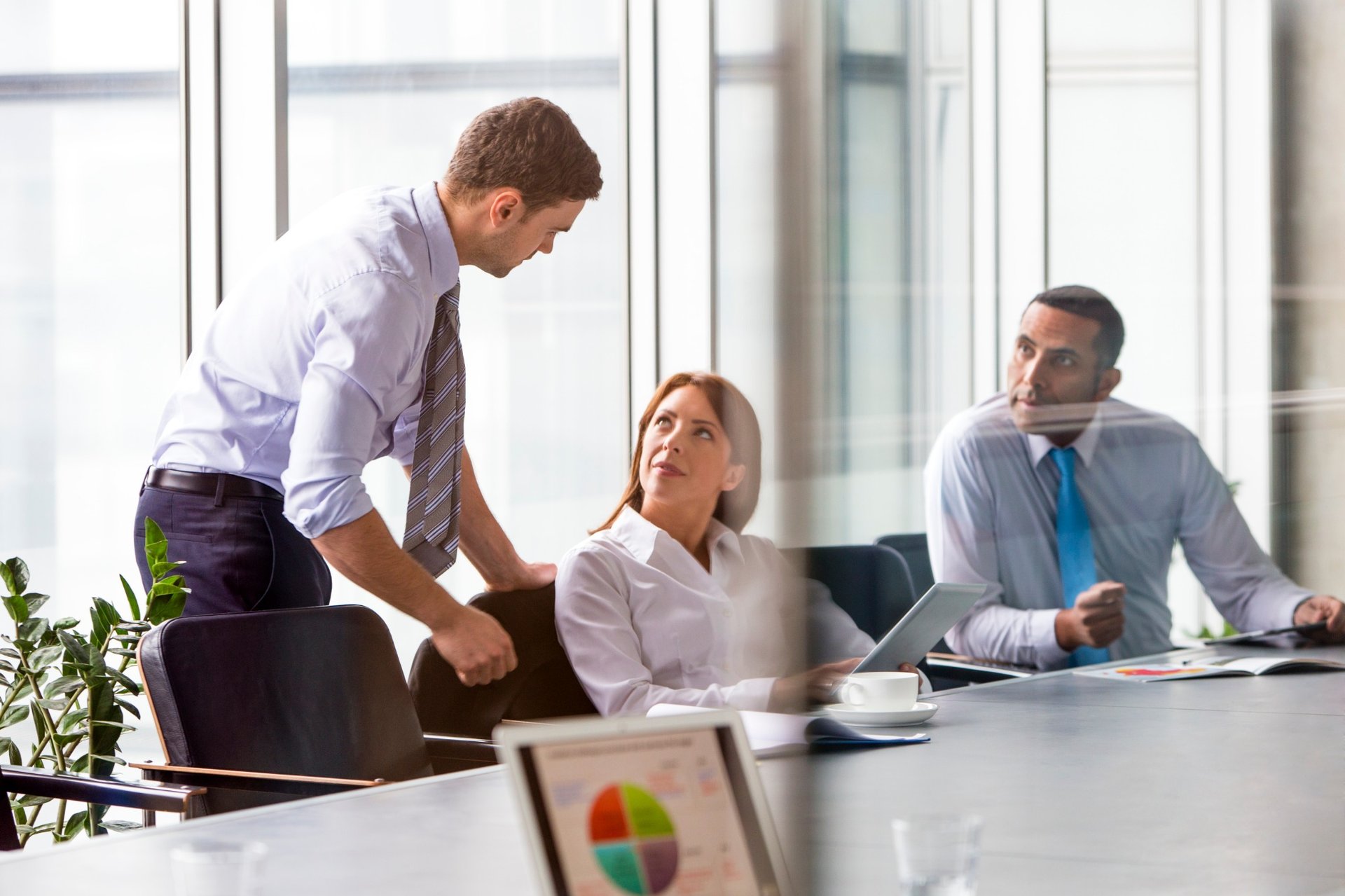 Three business colleagues in a modern office having a meeting with tablets and documents.