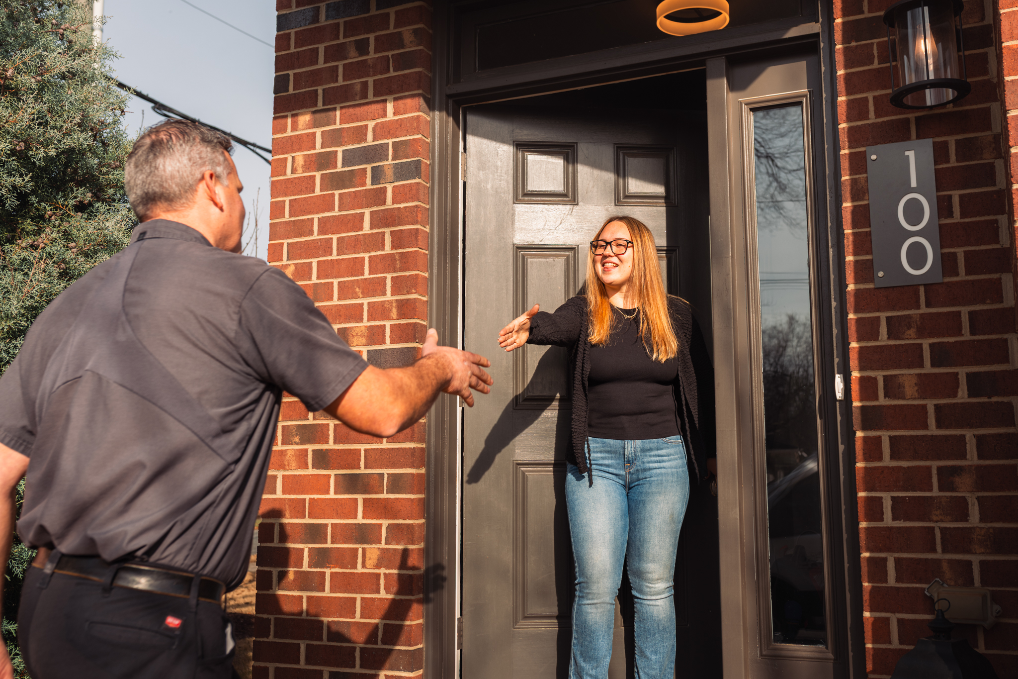 Charlotte Mechanical technician Tomasz meeting a customer at the front door of their home, reaching forward to shake hands with the customer.