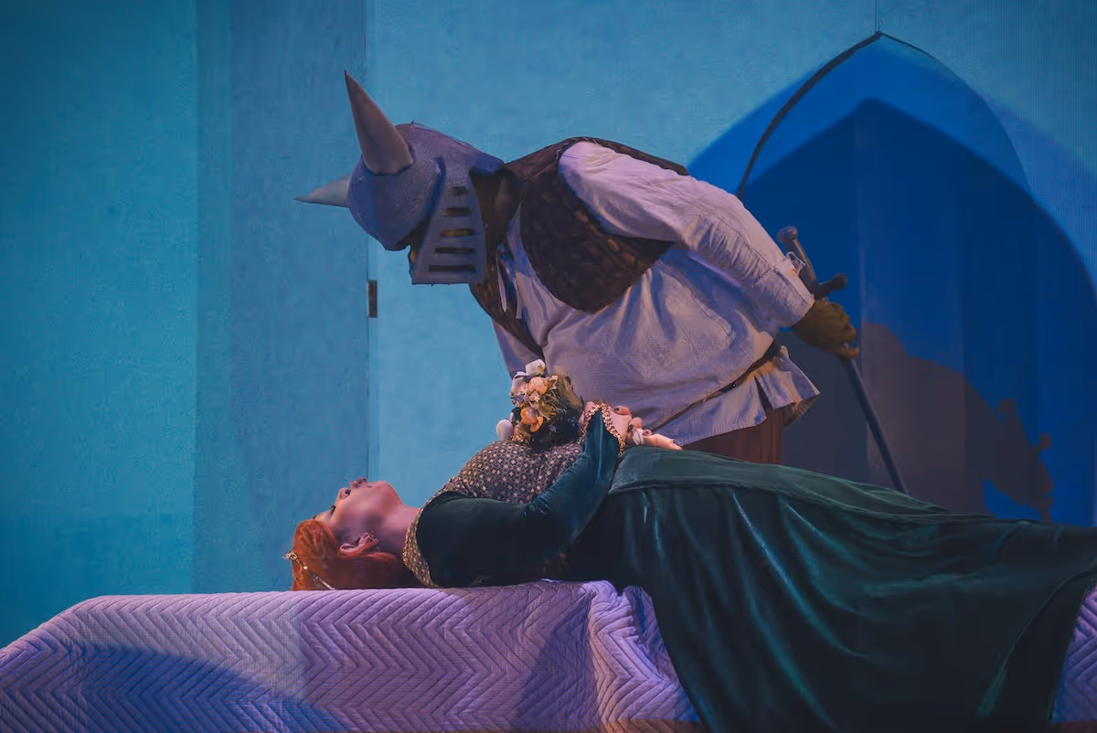 A woman laying on a bed next to a man in a costume.