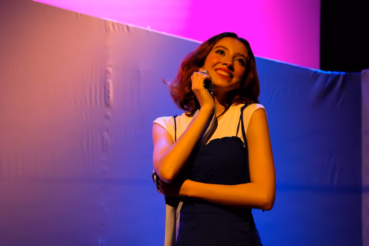 A woman talking on a cell phone in front of a purple background.