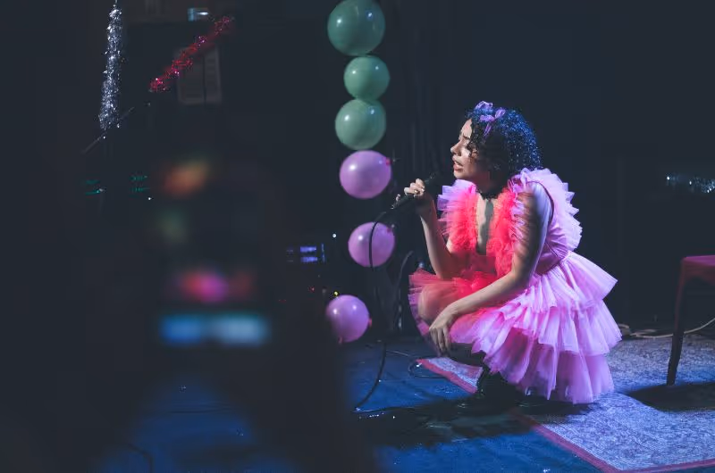 A woman in a pink dress sitting on a stage.