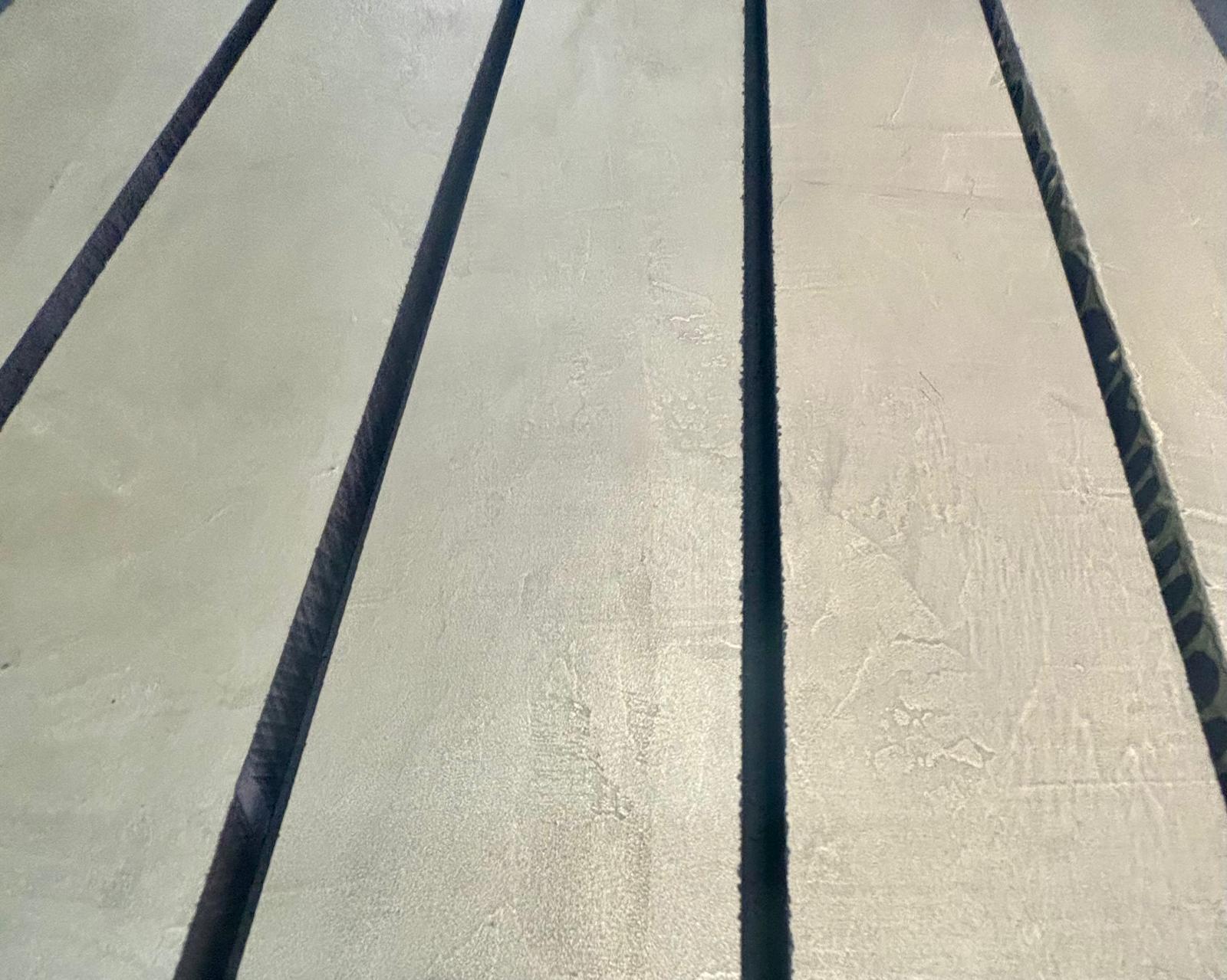 Close-up of brushed metal base beneath concrete tabletop