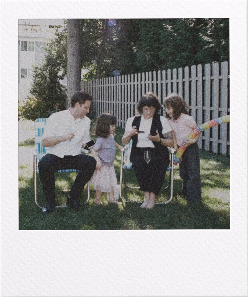 Four people sitting on lawn chairs in backyard with white picket fence