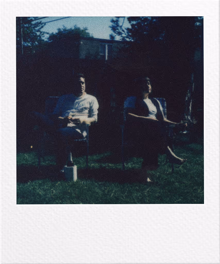 Two people sitting in chairs on a grassy lawn at dusk