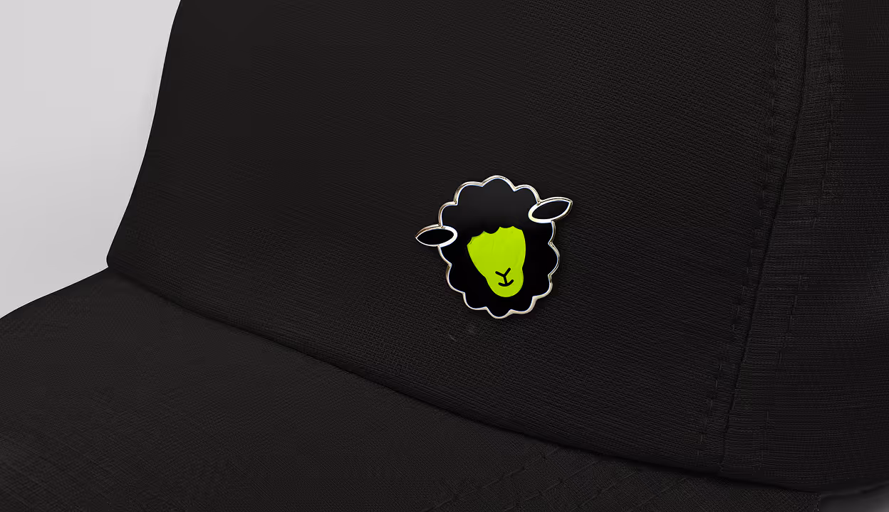 Green and black sheep pin on a dark textured background