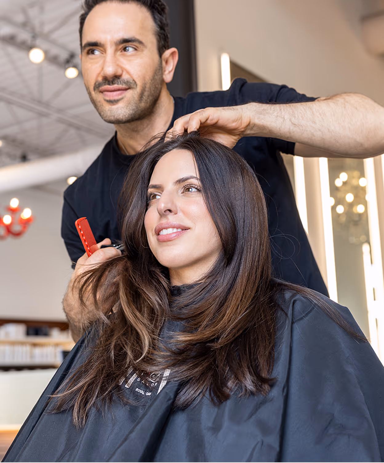 Hairstylist styling woman's long hair in a modern salon