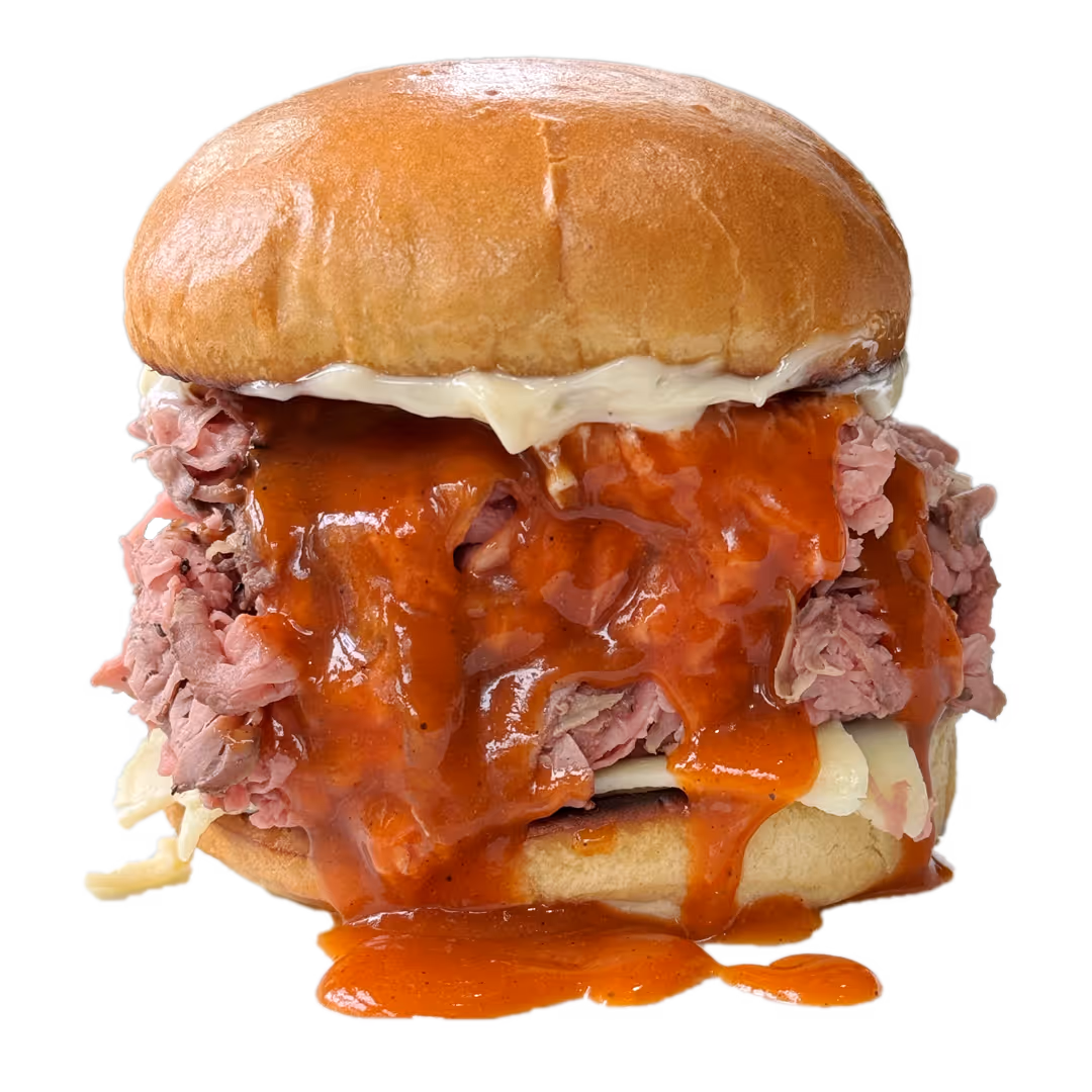 Close-up of a roast beef three-way sandwich with melted cheese, mayonnaise, and red barbecue sauce dripping over a soft bun.