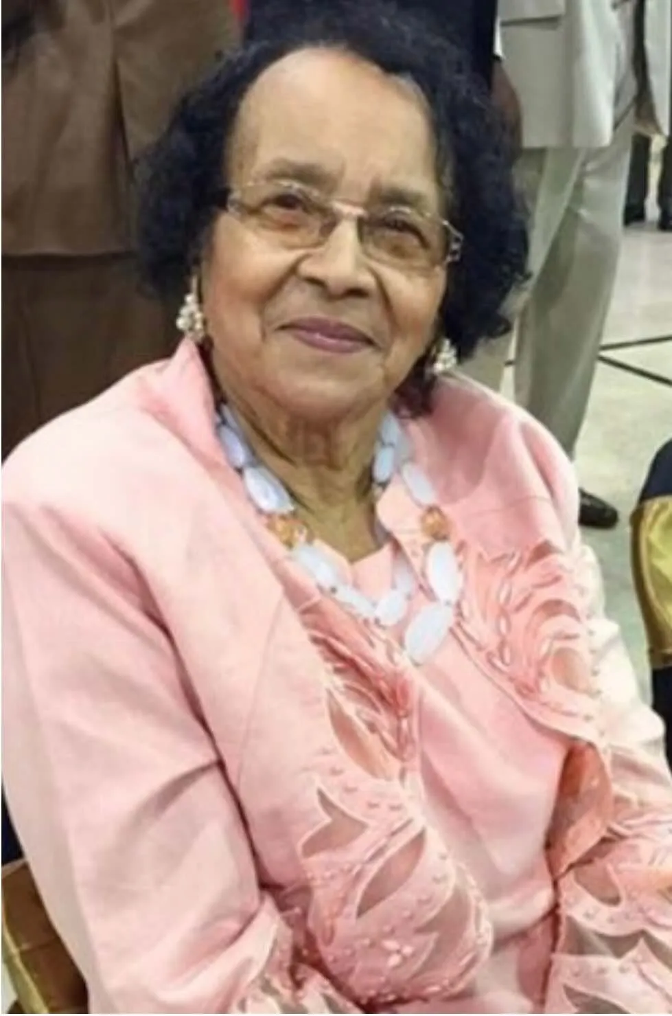 A woman wearing a pink shirt and glasses.