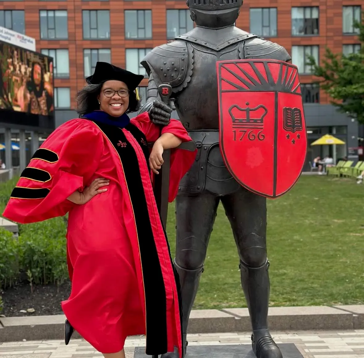 woman standing by rutgers statue after graduating with a PhD