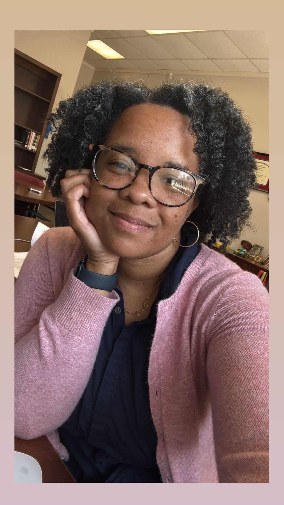 Black woman smiling at the camera wearing glasses