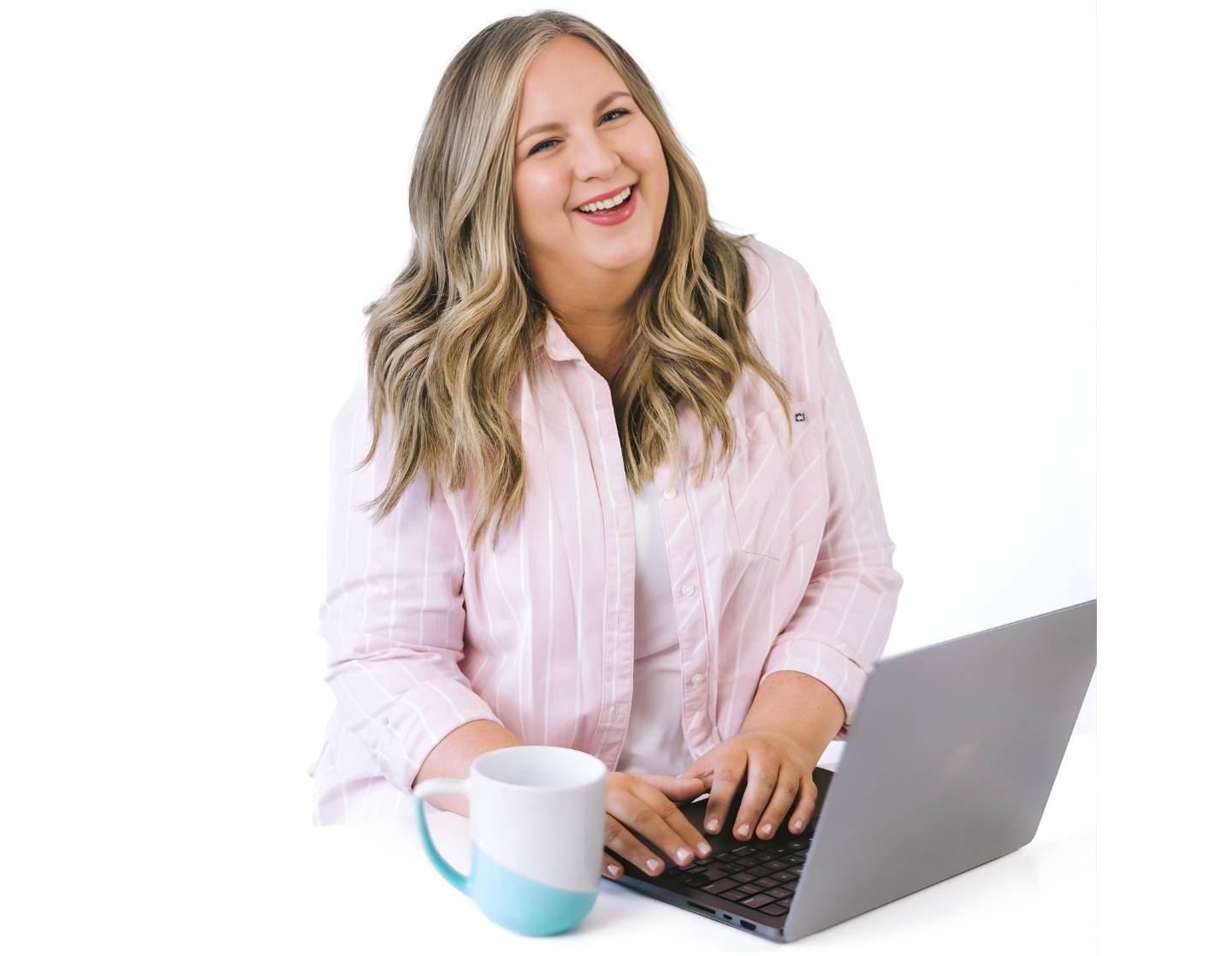 Jessica Chambers of Enlifen Co. smiling while sitting at a desk with a laptop and holding a coffee mug.