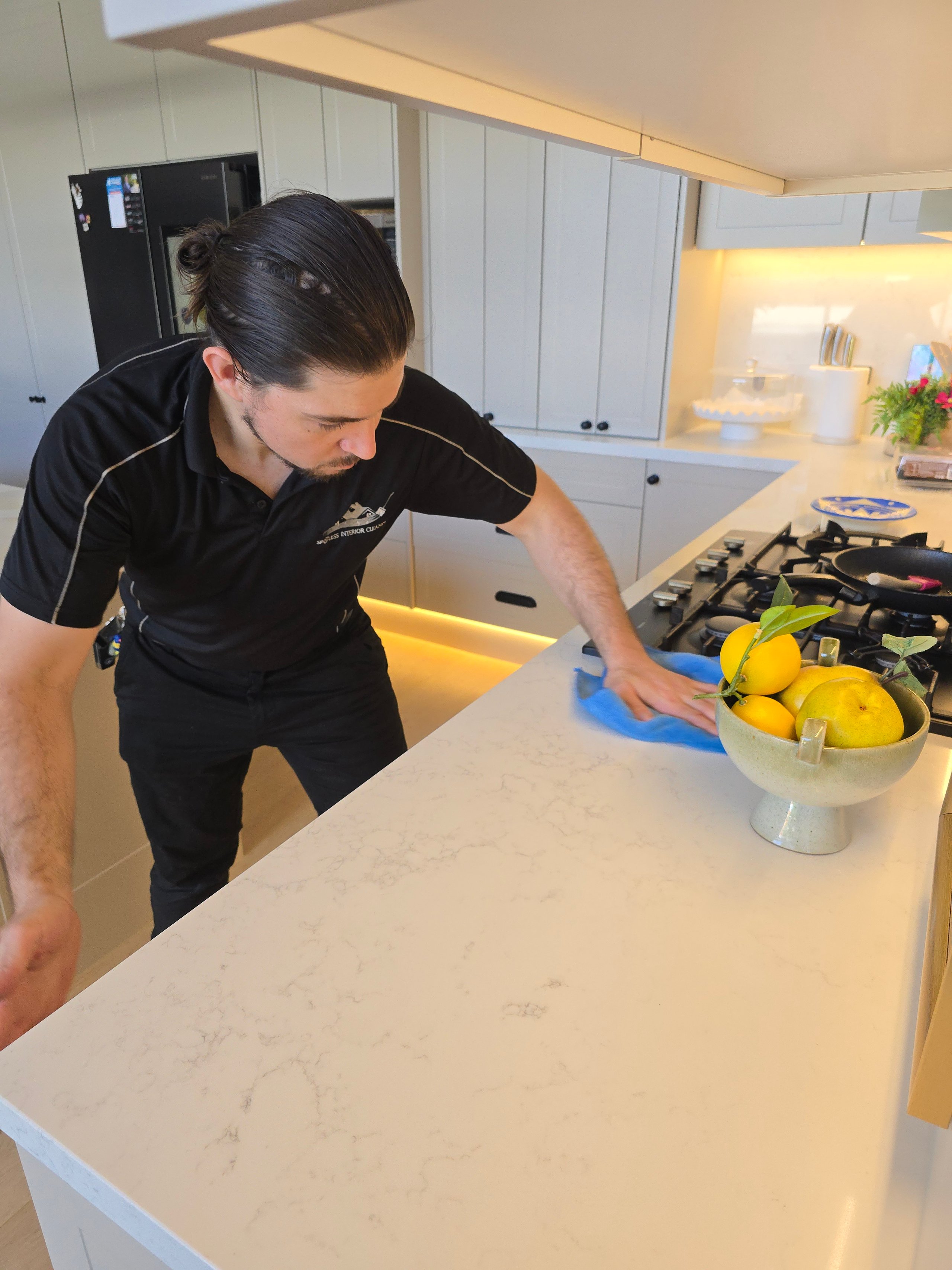 Deep clean of stone benchtop near cooktop - Spotless Interior Cleaning technician in Blacktown and Parramatta region.