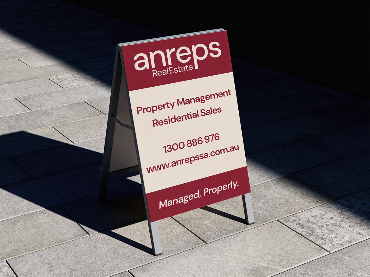 Anreps Real Estate A-frame street sign in burgundy and cream, from the Longshot Studio brand identity project
